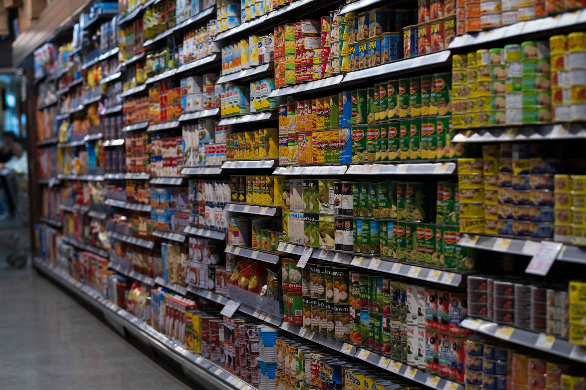 Supermarkedshylder fyldt med dåser og pakker i mange farver